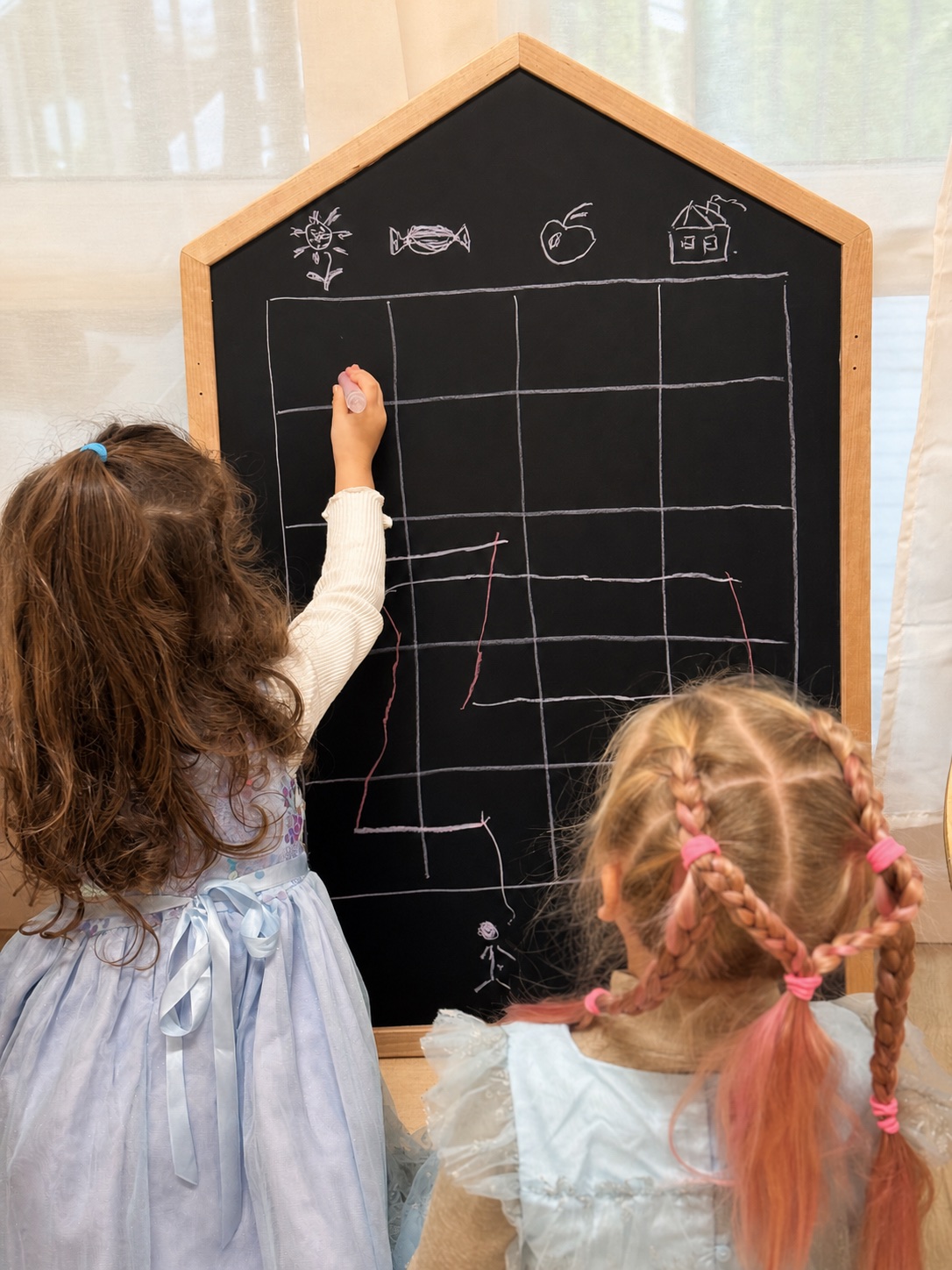 Two children creating a picture graph on a chalkboard during Math and Logic