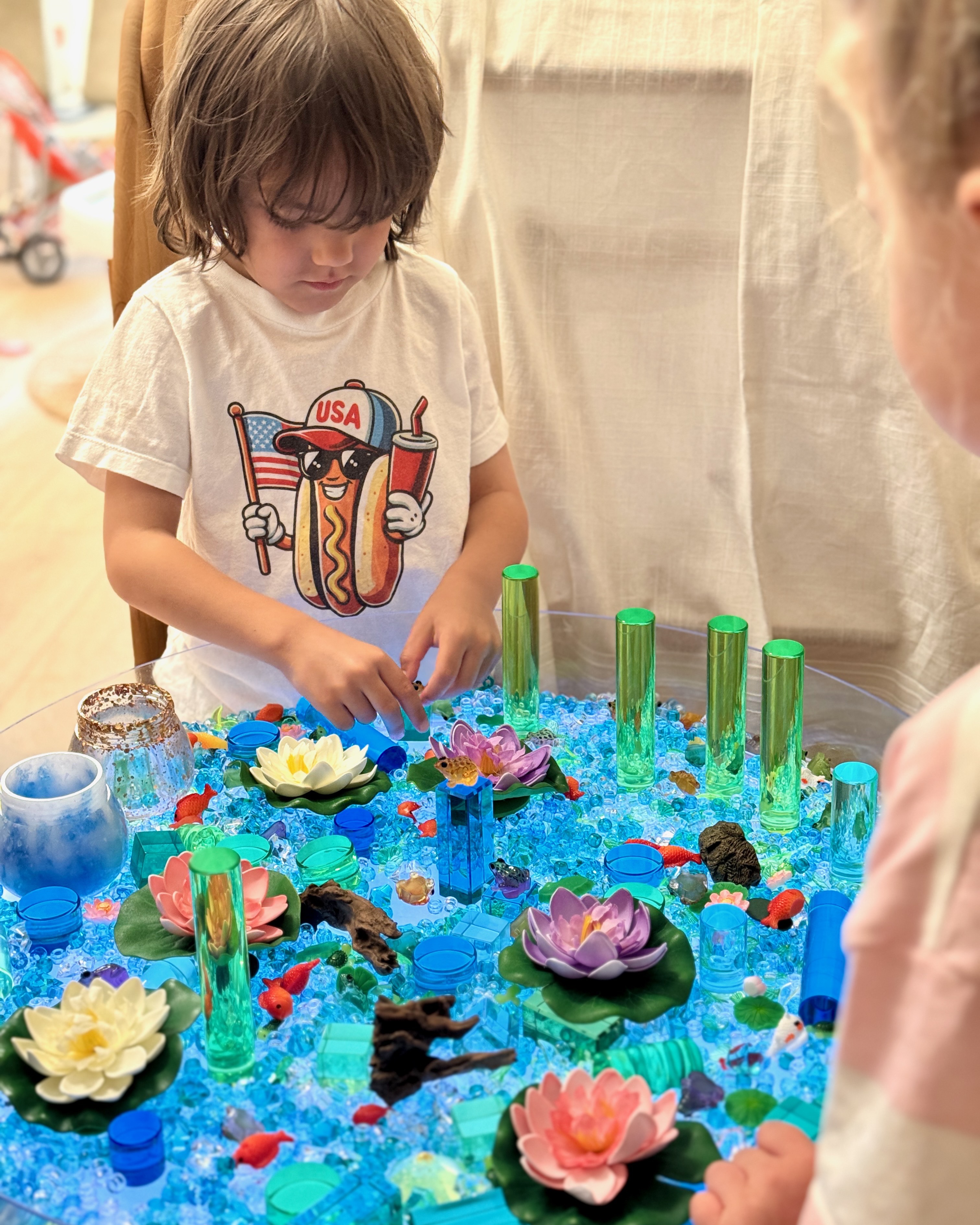 A child exploring a hands-on pond-life sensory invitation