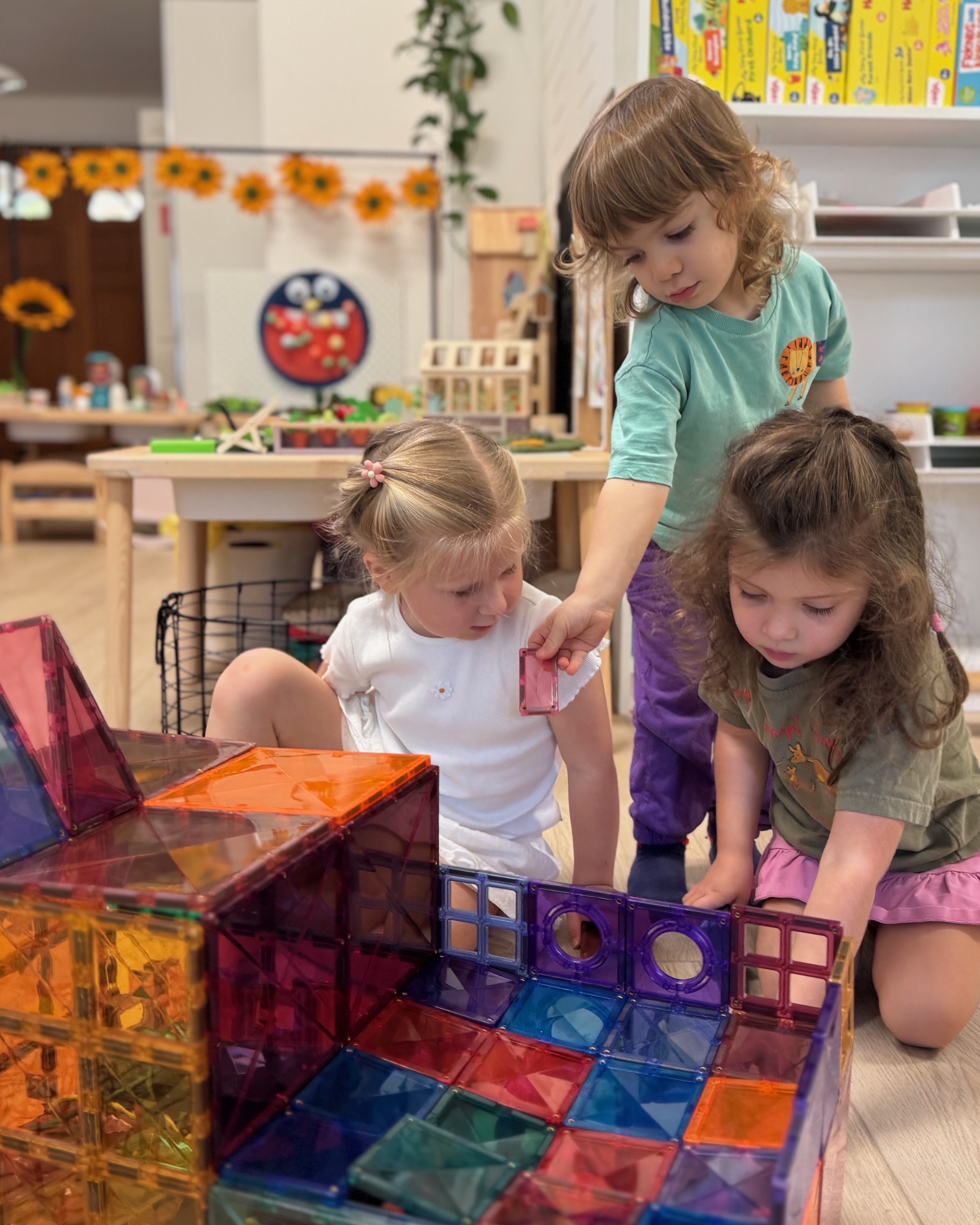 Children collaborating to build a large structure with magnetic tiles