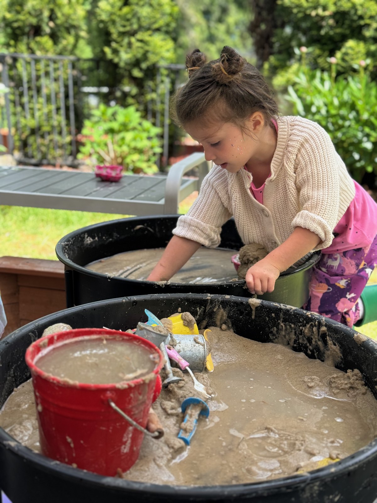 Child exploring mud and water at an outdoor sensory table