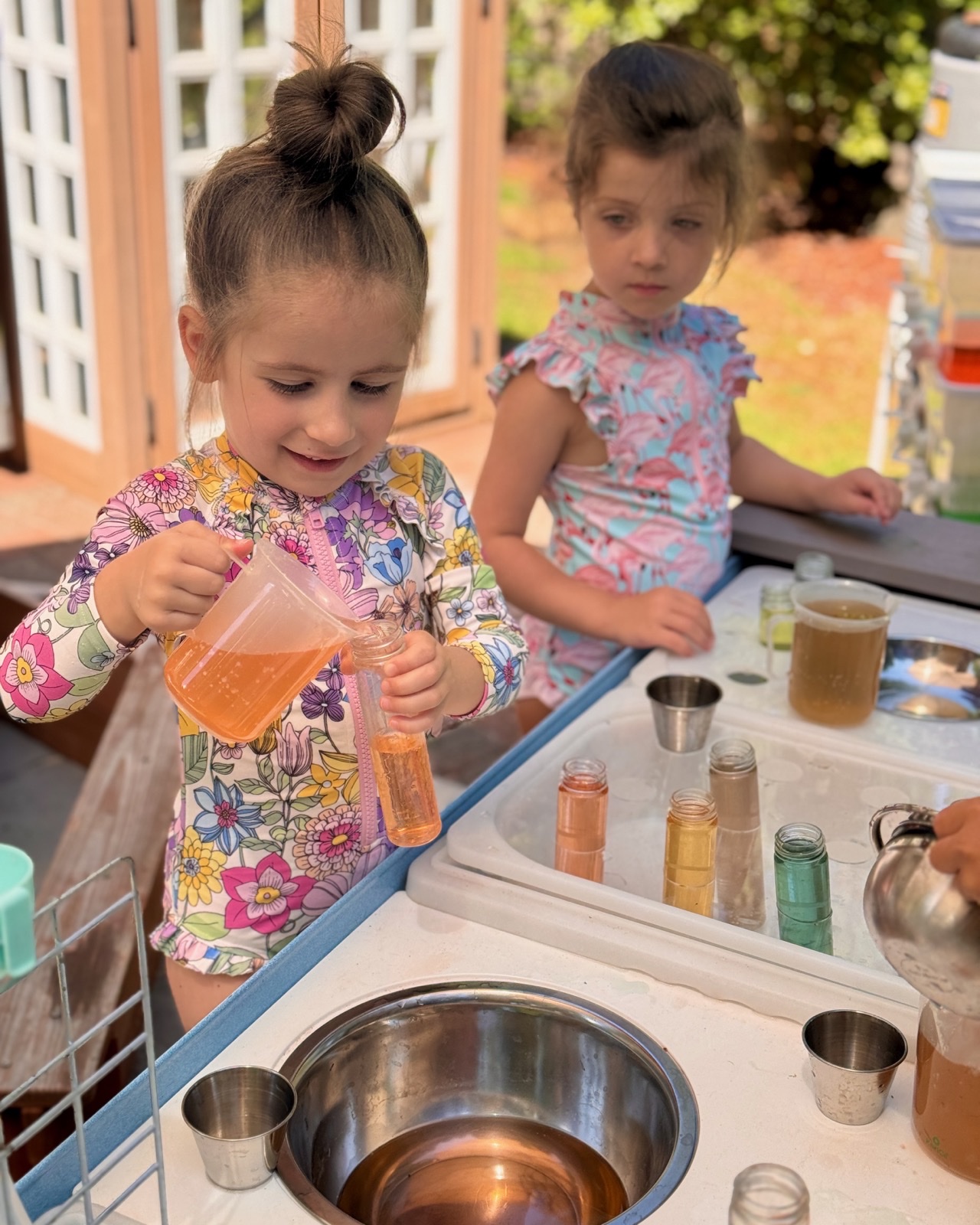 Children pouring and investigating colorful liquids during an outdoor sensory exploration