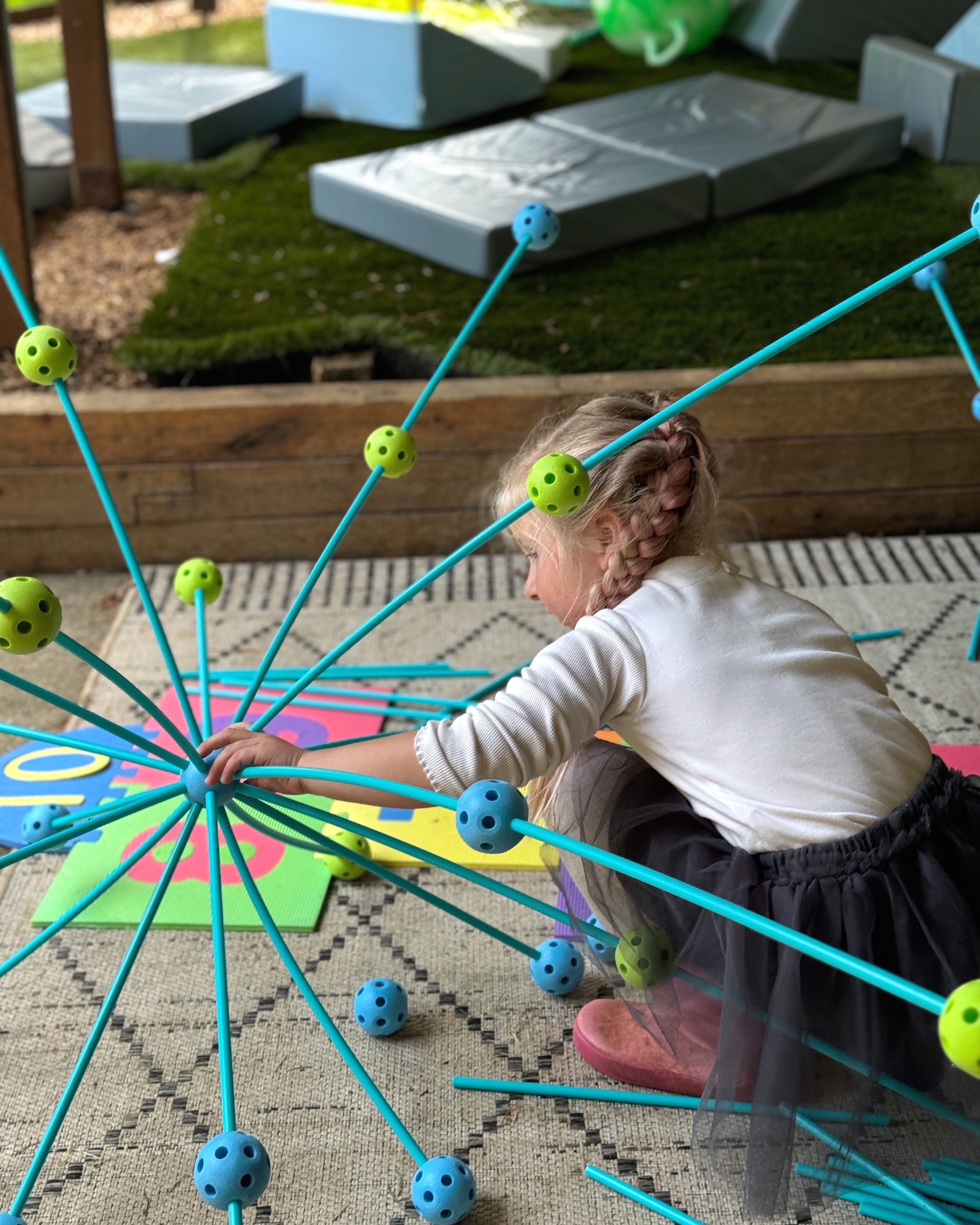 A child constructing a large open-ended structure during an outdoor STEAM exploration