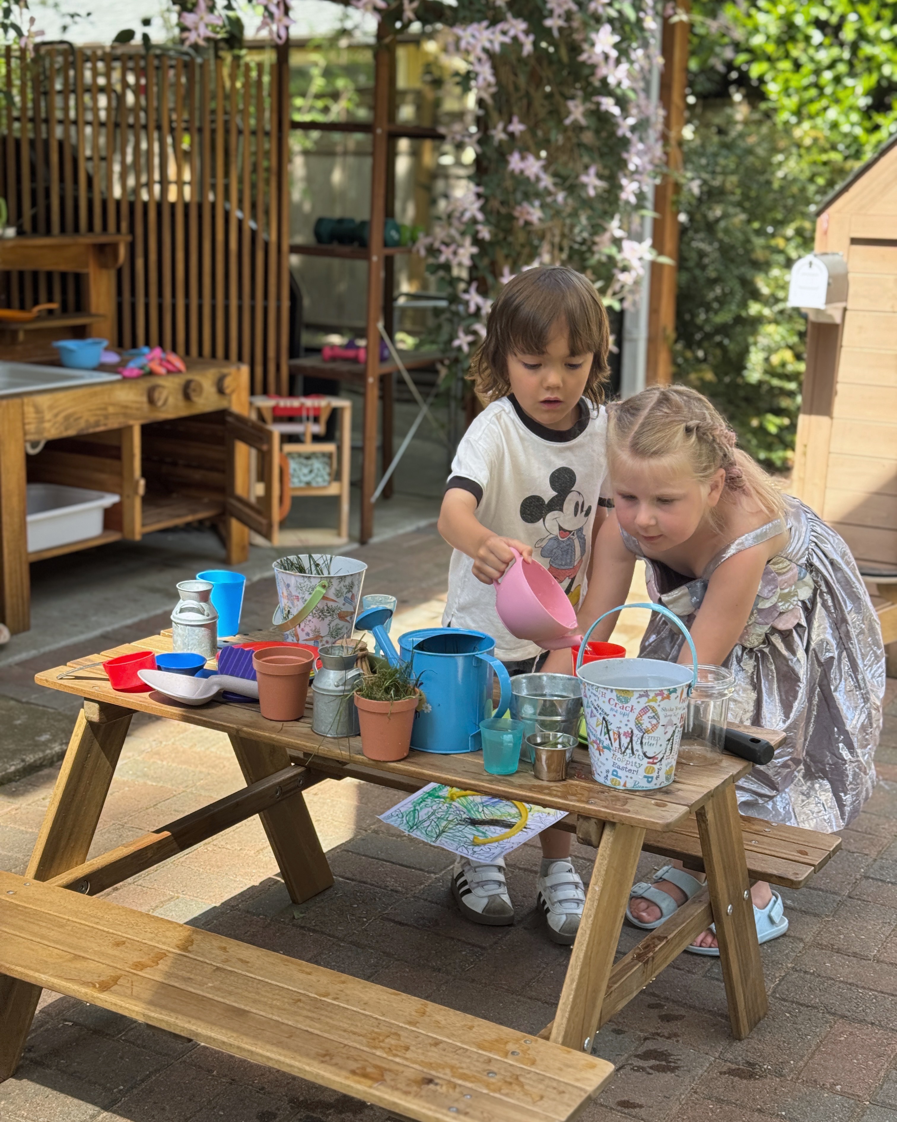 Children pouring and experimenting with water and containers outdoors