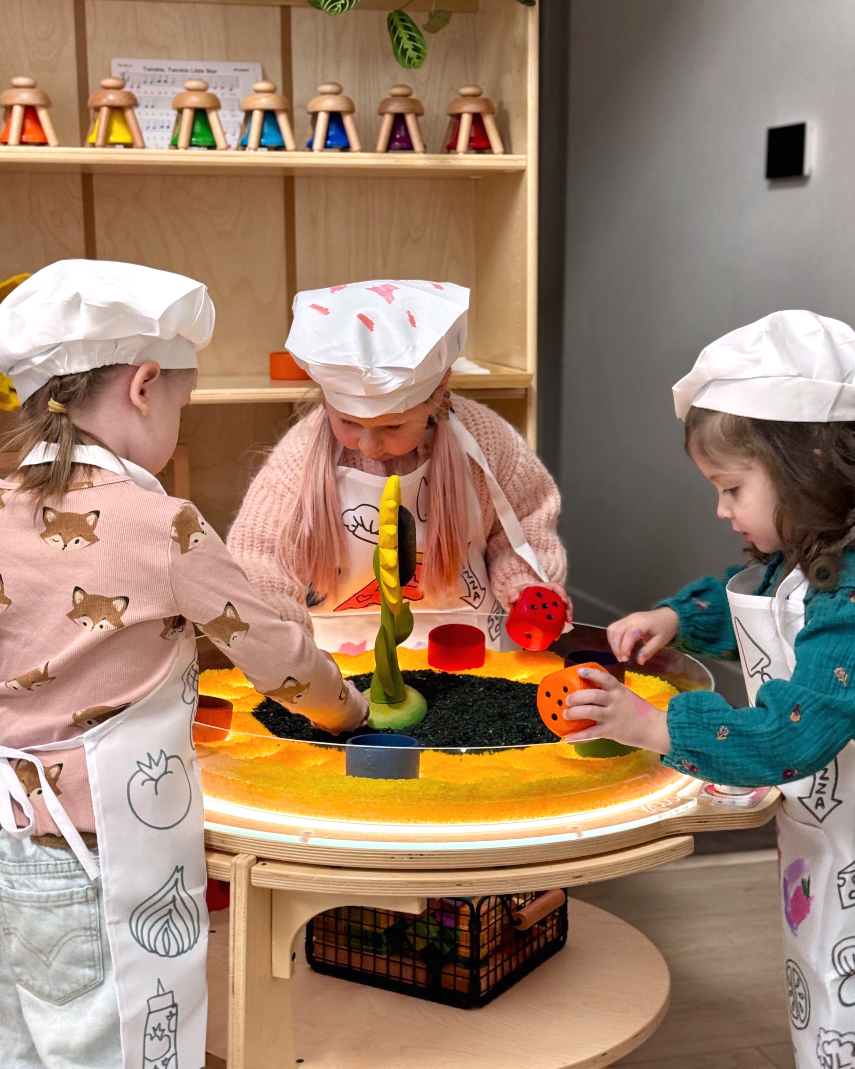 Children wearing chef hats and aprons during a hands-on enrichment class
